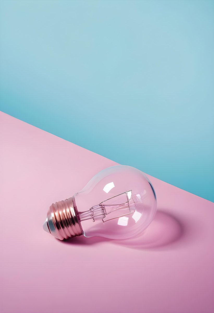 A Clear Light Bulb Lying On A Pink Surface With A Blue Background The Bulb Has A Classic Filament Design Visible Inside The Color Contrast Between The Pink And Blue Creates A Vibrant Aesthetic 26 B366