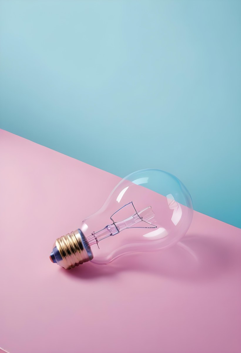A Clear Light Bulb Lying On A Pink Surface With A Blue Background The Bulb Has A Classic Filament Design Visible Inside The Color Contrast Between The Pink And Blue Creates A Vibrant Aesthetic 32 Baf2