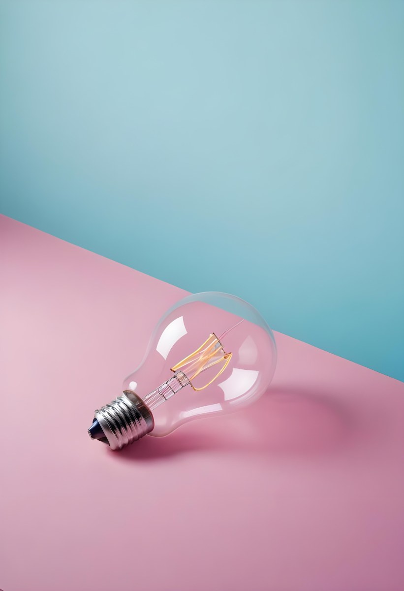 A Clear Light Bulb Lying On A Pink Surface With A Blue Background The Bulb Has A Classic Filament Design Visible Inside The Color Contrast Between The Pink And Blue Creates A Vibrant Aesthetic 33 7cf5