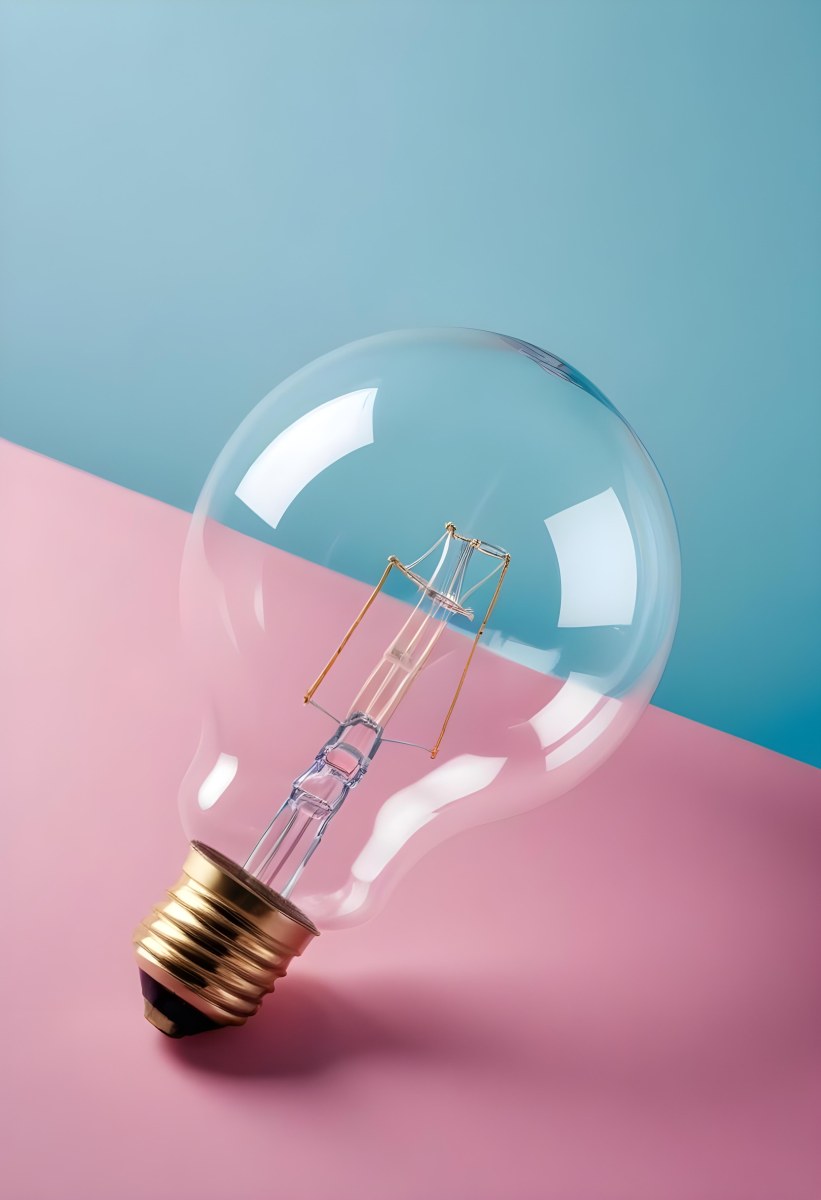 A Clear Light Bulb Lying On A Pink Surface With A Blue Background The Bulb Has A Classic Filament Design Visible Inside The Color Contrast Between The Pink And Blue Creates A Vibrant Aesthetic 7 436e