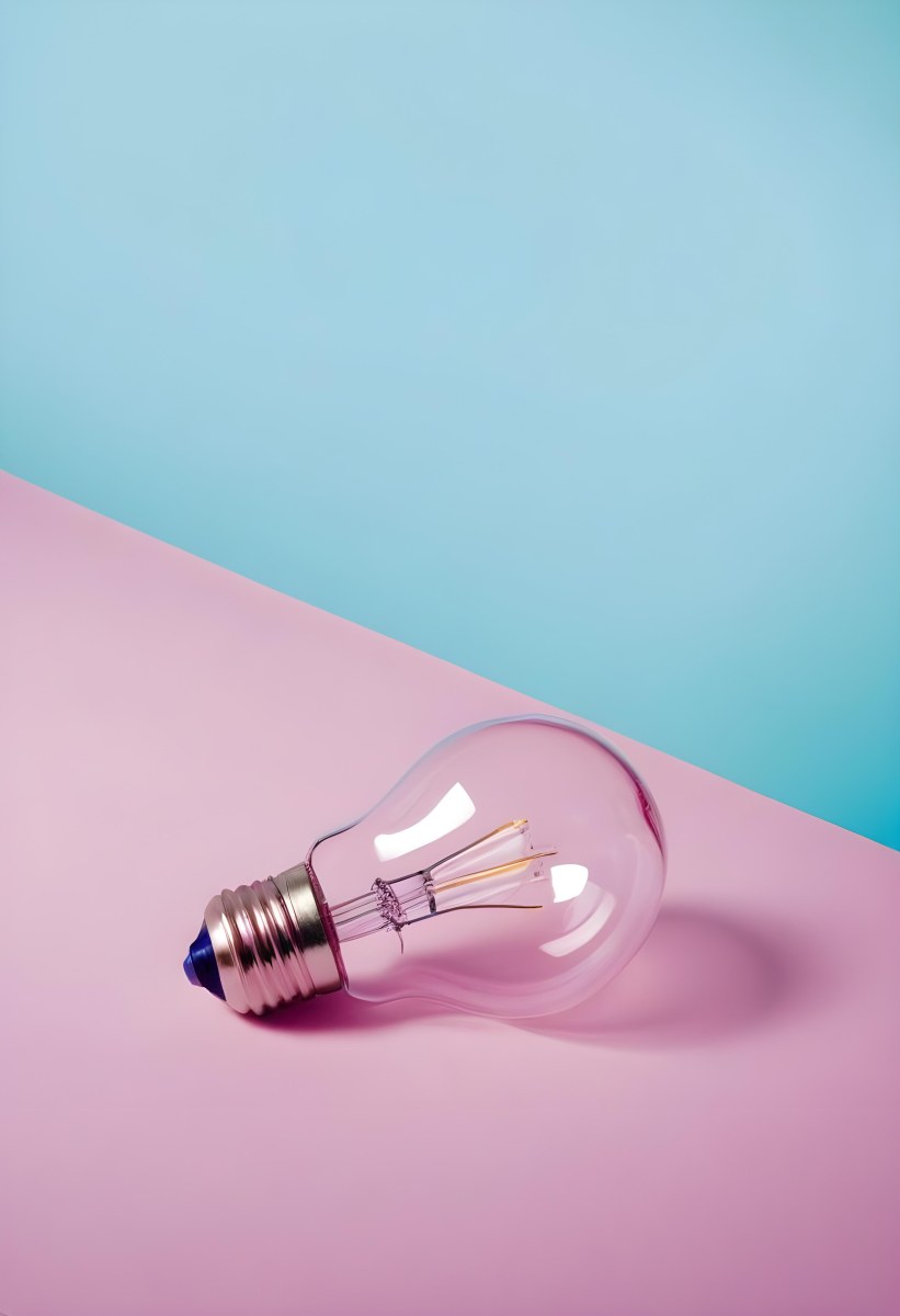 A Clear Light Bulb Lying On A Pink Surface With A Blue Background The Bulb Has A Classic Filament Design Visible Inside The Color Contrast Between The Pink And Blue Creates A Vibrant Aesthetic 8 Cdfc