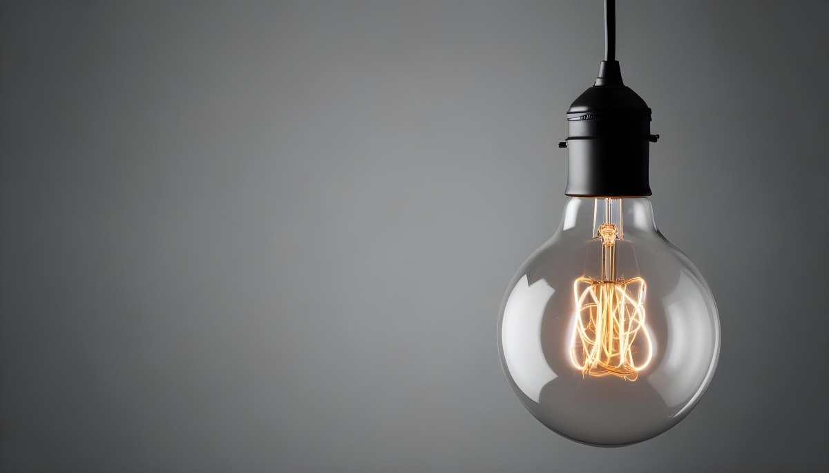 A Clear Light Bulb With A Black Socket Hanging From The Ceiling The Background Is A Solid Black Color 2 181d