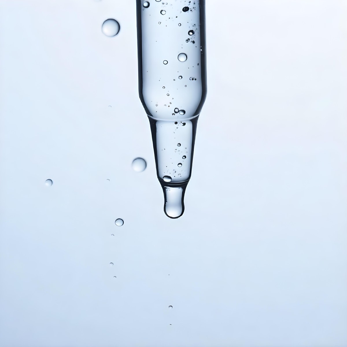 A Close Up Of A Glass Pipette With Water Droplets Against A Blue Background 8 Bafb