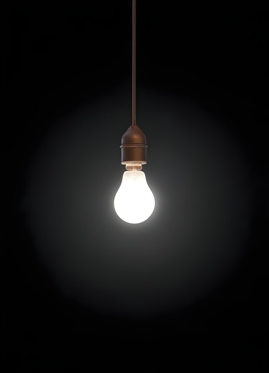 A Light Bulb Hanging From The Ceiling The Bulb Is Glowing Brightly The Background Is Black The Light Is Casting A Soft Glow 16 65fa