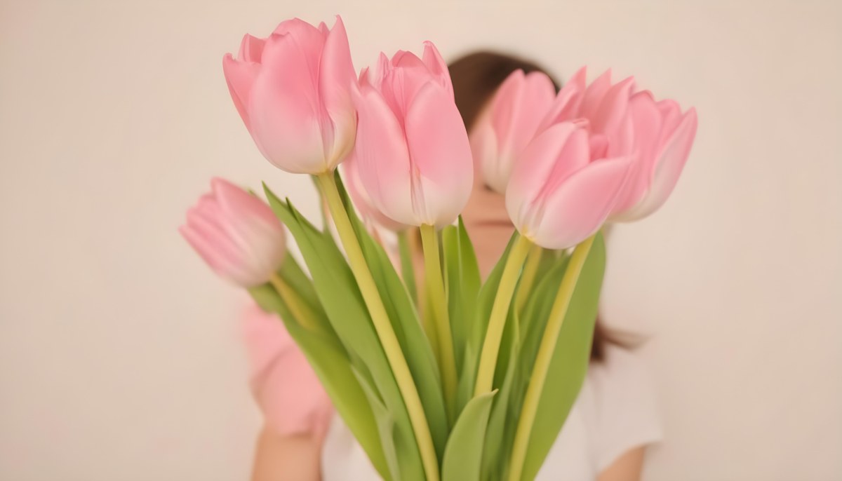 A Bouquet Of Pink Tulips In Front Of A Blurry White Woman 25 Years Old With Brown Hair In A Studio With A White Background 6 A162