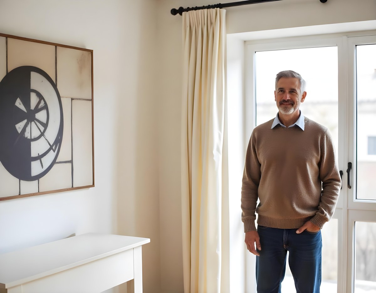 A Middle Aged Caucasian Man With Short Gray Hair Standing By A Window In A Bedroom Looking Outside At A Cityscape During Daytime 10 D129