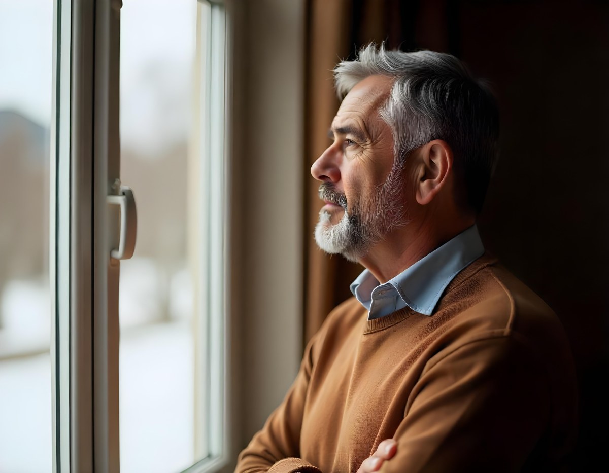 A Middle Aged Caucasian Man With Short Gray Hair Standing By A Window In A Bedroom Looking Outside At A Cityscape During Daytime 6 Ea94