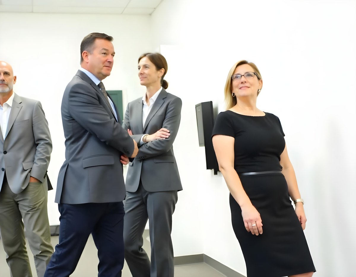 A Middle Aged Caucasian Woman With Short Blonde Hair And A Middle Aged Caucasian Man With Gray Hair And Glasses Both Smiling And Dressed Formally 7 5525