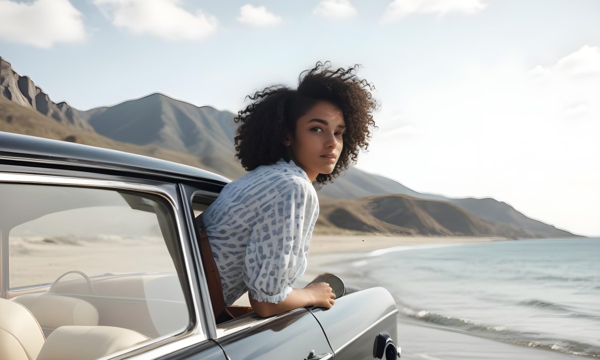 A Young Black Woman With Curly Hair Looking Out The Window Of A Vintage Car On A Sunny Beach With Mountains In The Background 1 5d65