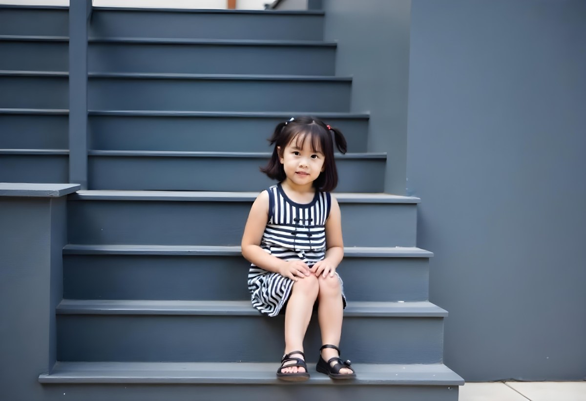 An Asian Girl 6 Years Old Black Hair Sitting On Gray Stairs Wearing A Striped Dress And Black Shoes Gray Background 37 437f