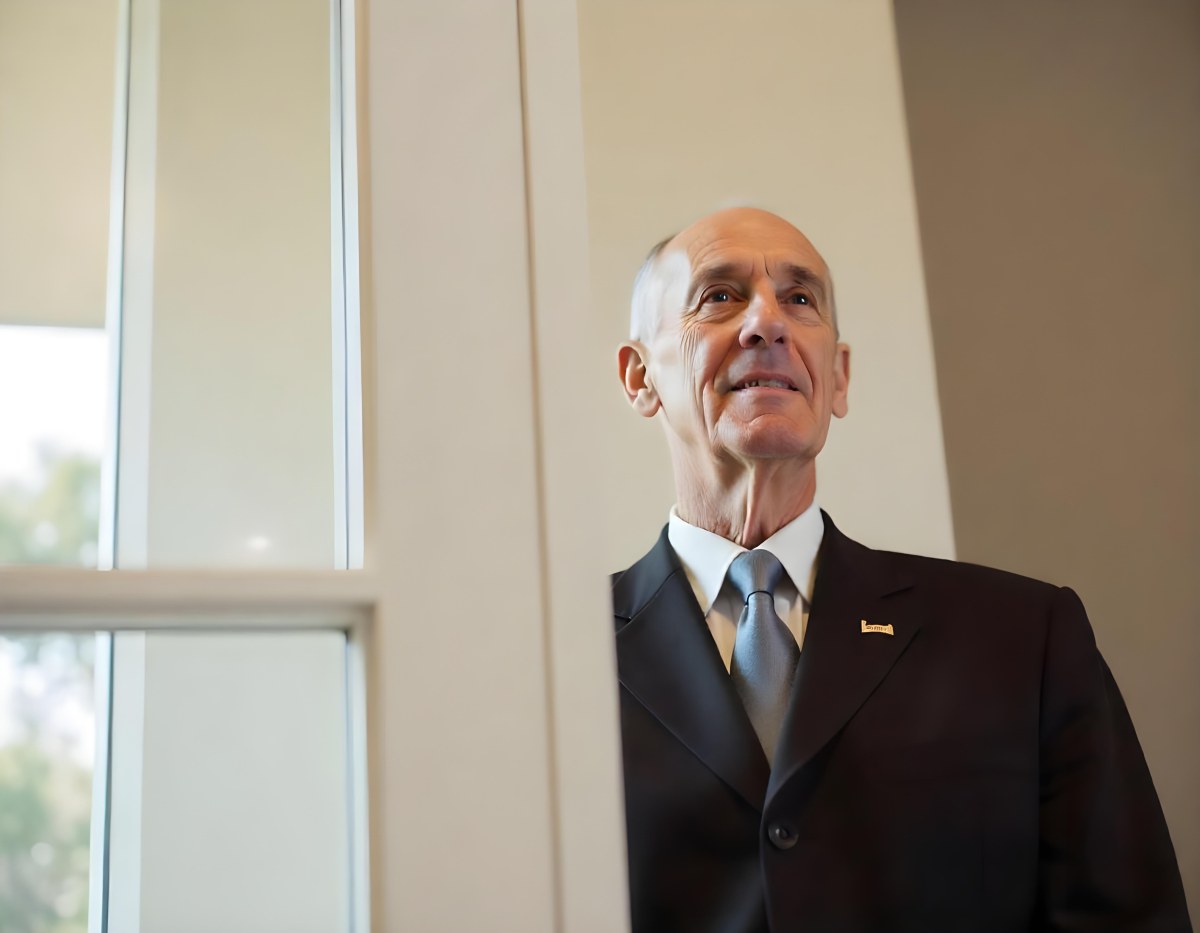 An Elderly Caucasian Man With Gray Hair Wearing A Dark Suit And Tie Standing In Front Of A Window 15 50c7