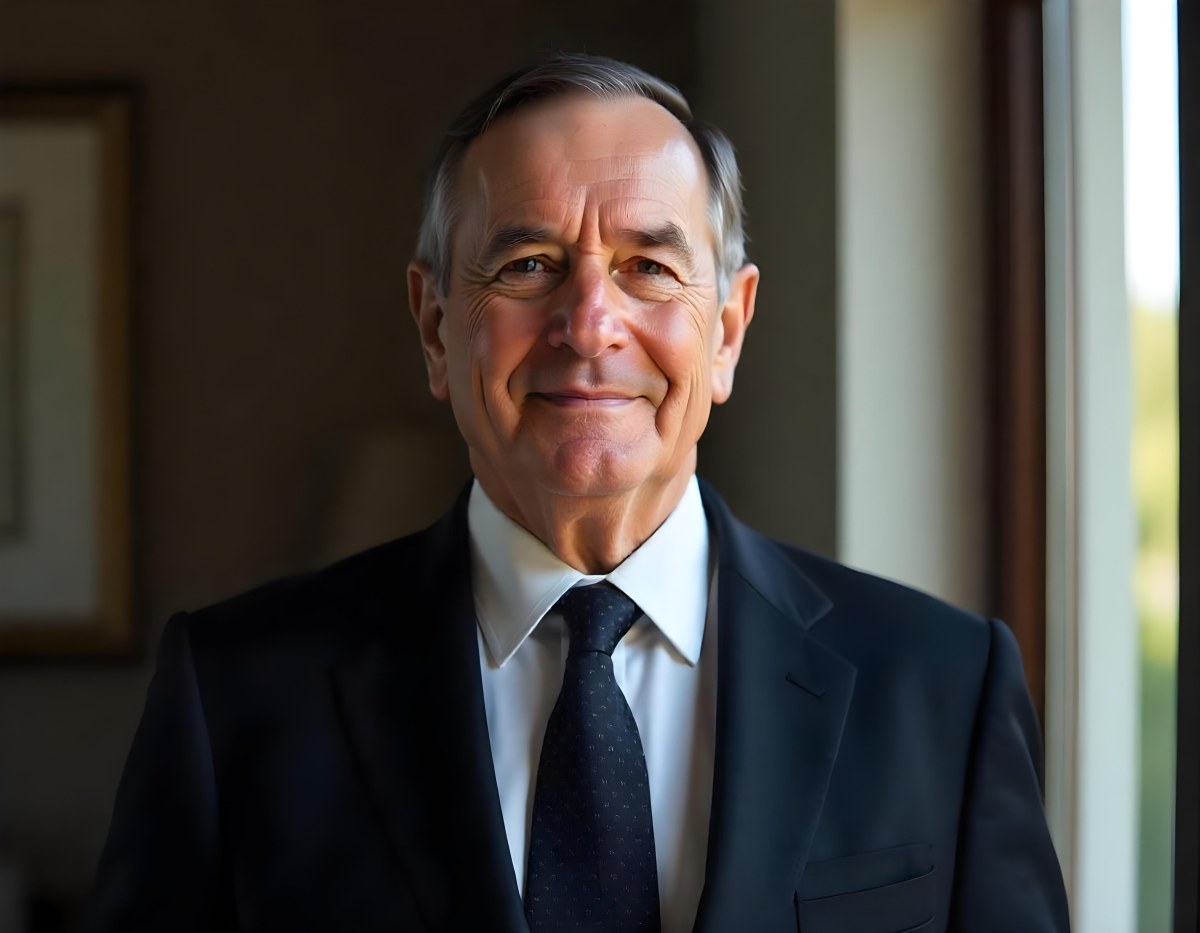An Elderly Caucasian Man With Gray Hair Wearing A Dark Suit And Tie Standing In Front Of A Window 4 8298