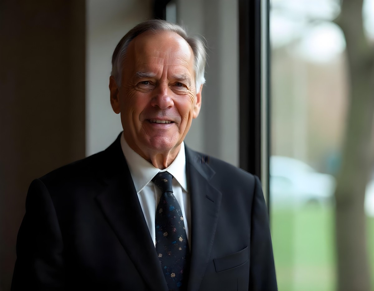 An Elderly Caucasian Man With Gray Hair Wearing A Dark Suit And Tie Standing In Front Of A Window 7 9346