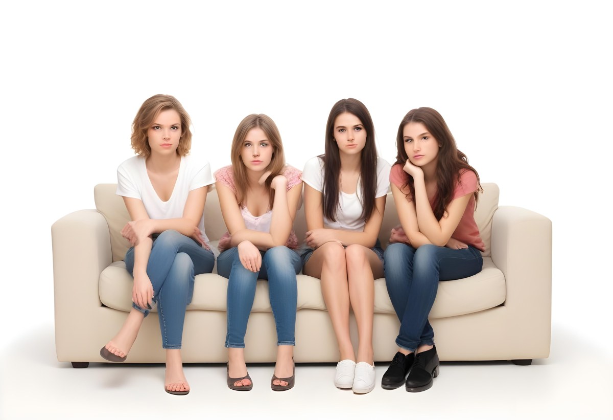 Four Young Caucasian Women Approximately 20 25 Years Old With Varying Hair Colors And Styles Long Sitting On A White Couch And Looking At The Camera 6 6a62