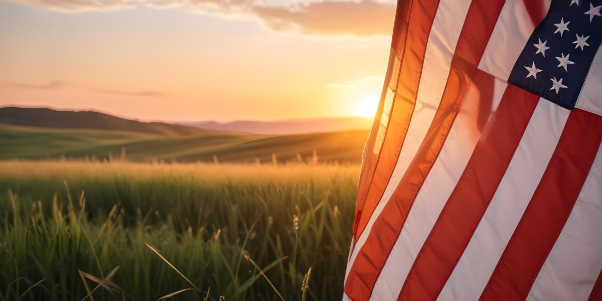 A Close Up View Of An American Flag Against A Scenic Sunset Landscape With A Grassy Field And A Bright Orange Sky 37 Fe27