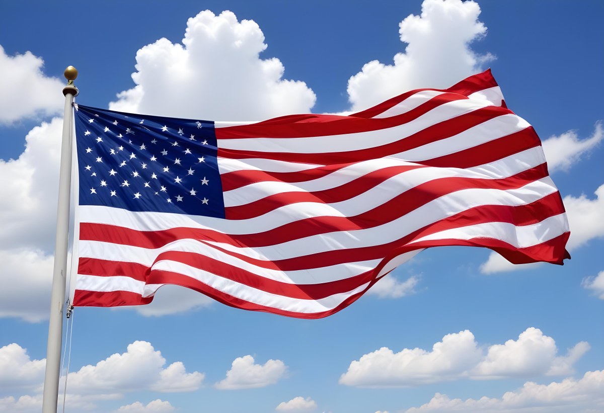 American Flag Waving In The Wind With Its Red And White Stripes And Blue Field Of Stars Against A Blue Sky With White Clouds 12 7193