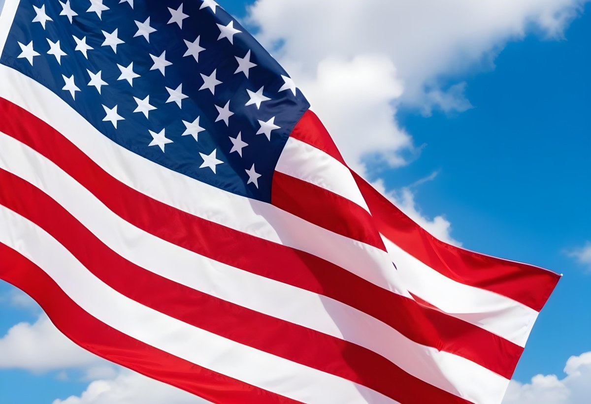 American Flag Waving In The Wind With Its Red And White Stripes And Blue Field Of Stars Against A Blue Sky With White Clouds 13 34bf