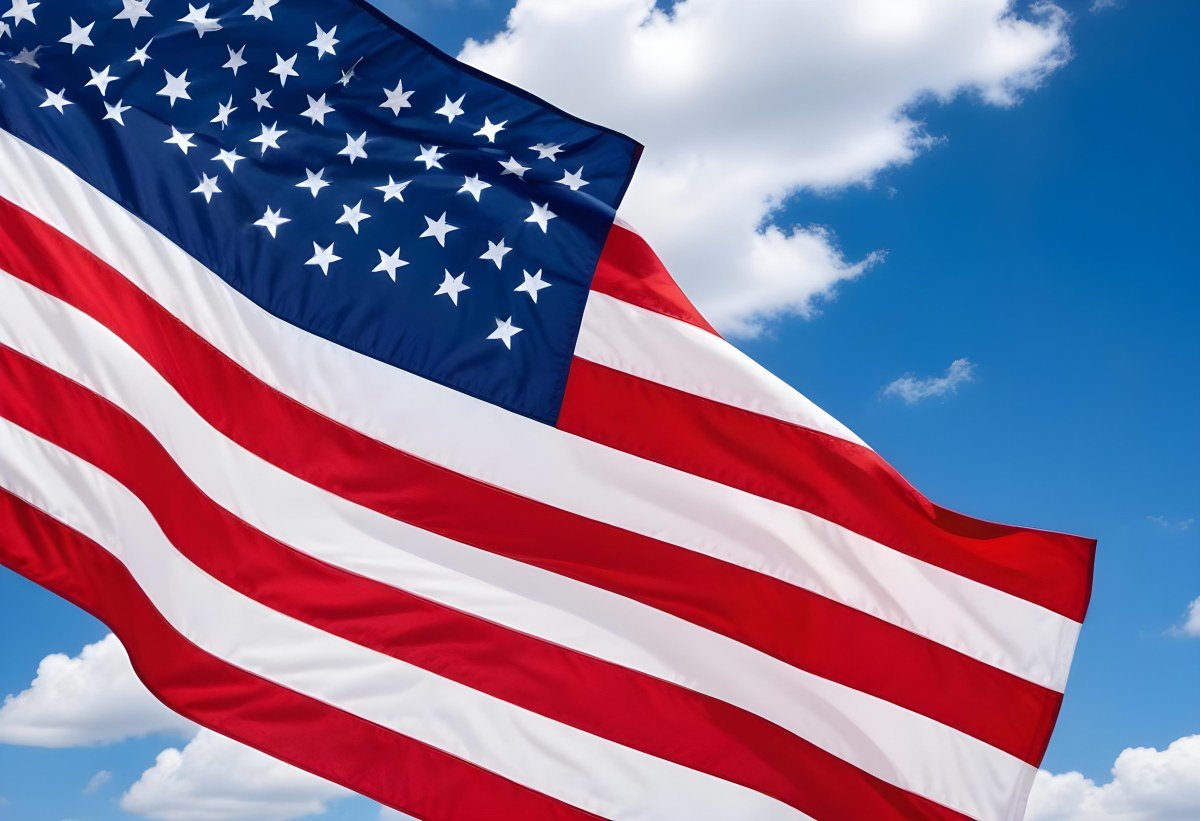 American Flag Waving In The Wind With Its Red And White Stripes And Blue Field Of Stars Against A Blue Sky With White Clouds 23 15e5