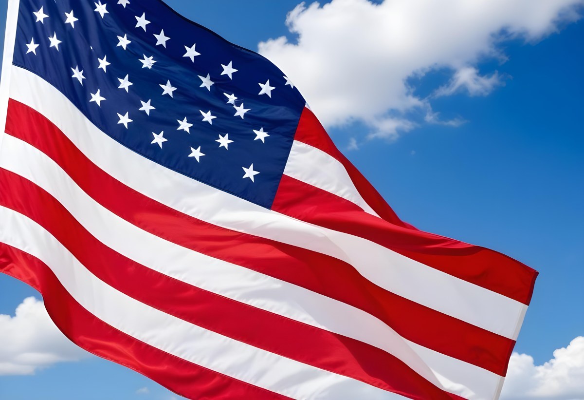 American Flag Waving In The Wind With Its Red And White Stripes And Blue Field Of Stars Against A Blue Sky With White Clouds 3 7a33
