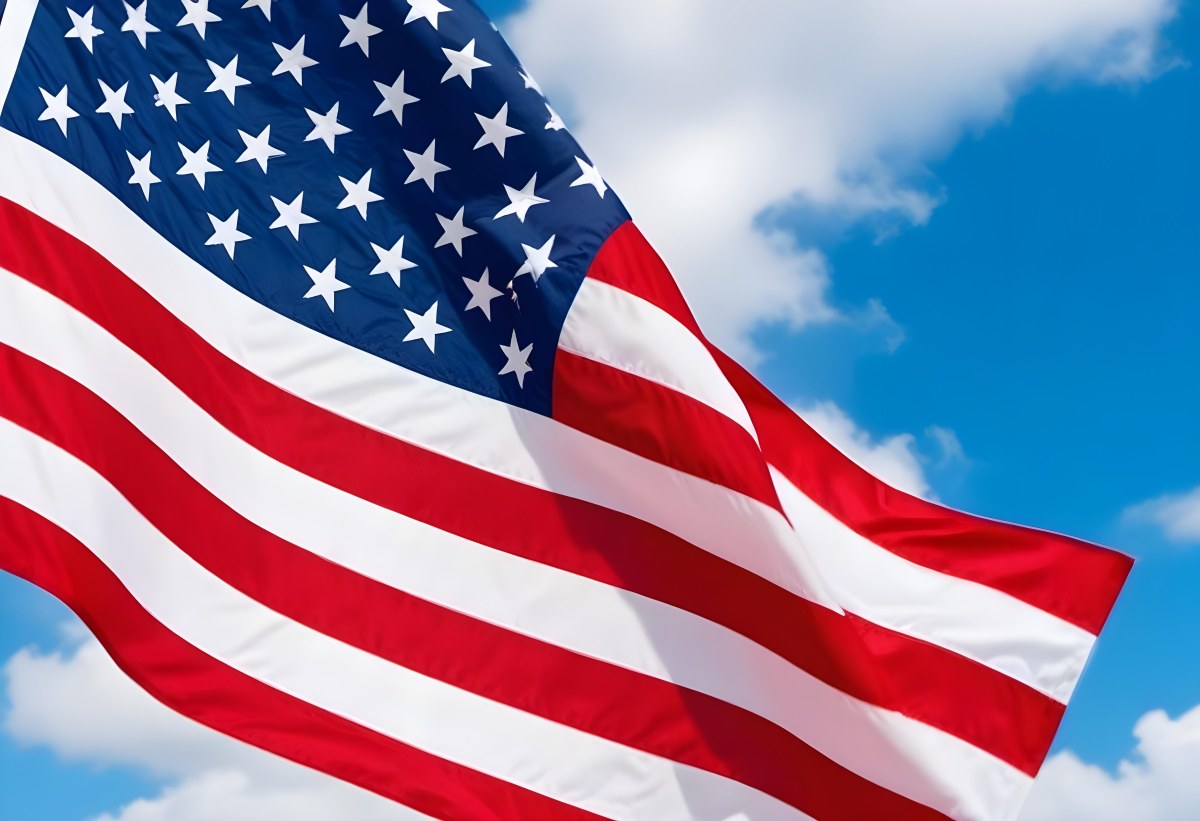 American Flag Waving In The Wind With Its Red And White Stripes And Blue Field Of Stars Against A Blue Sky With White Clouds 4 31f5
