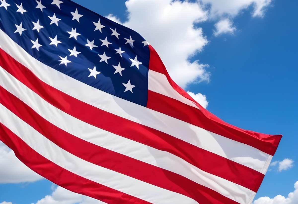 American Flag Waving In The Wind With Its Red And White Stripes And Blue Field Of Stars Against A Blue Sky With White Clouds 5 Ea62