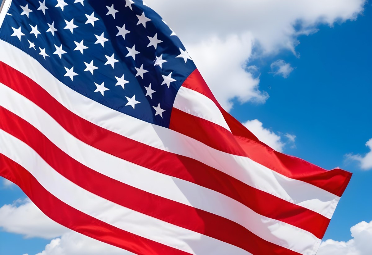 American Flag Waving In The Wind With Its Red And White Stripes And Blue Field Of Stars Against A Blue Sky With White Clouds 6 4ab2