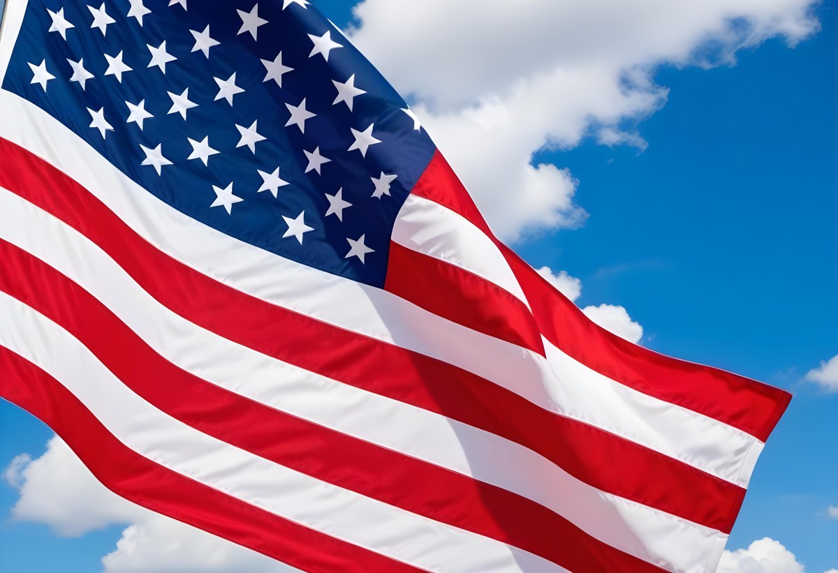 American Flag Waving In The Wind With Its Red And White Stripes And Blue Field Of Stars Against A Blue Sky With White Clouds 8 1733