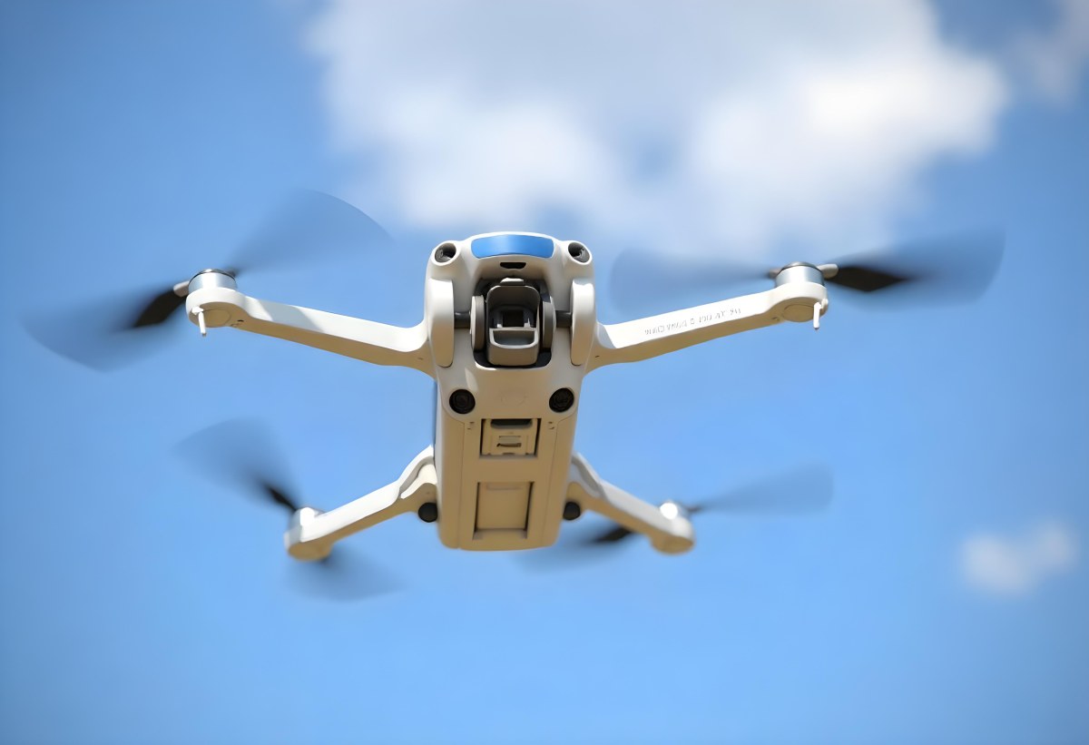 A Blue Dji Mini 3 Pro Drone With Blue Propellers In Mid Air Against A Bright Blue Sky With Scattered White Clouds 10 09ae
