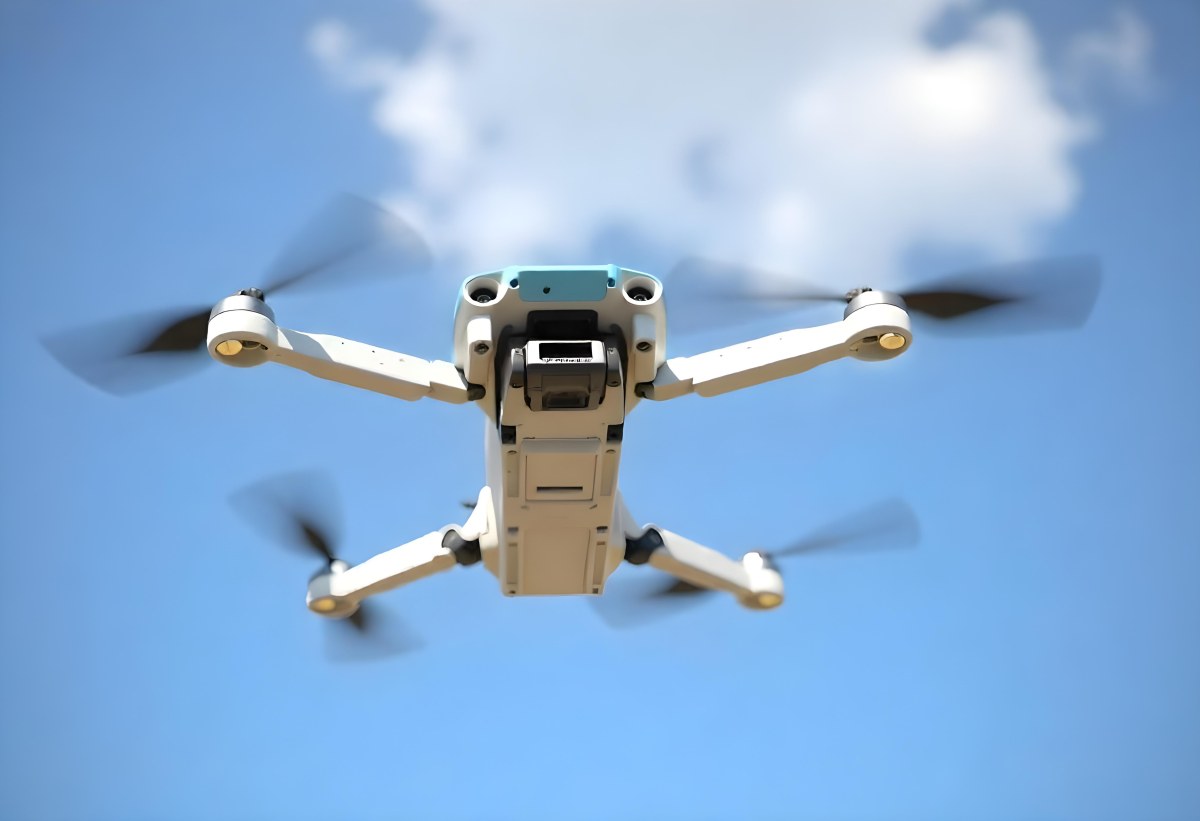 A Blue Dji Mini 3 Pro Drone With Blue Propellers In Mid Air Against A Bright Blue Sky With Scattered White Clouds 18 775b