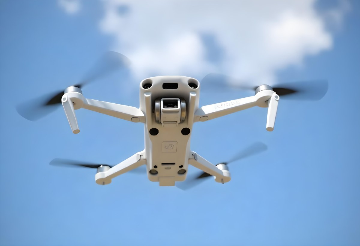 A Blue Dji Mini 3 Pro Drone With Blue Propellers In Mid Air Against A Bright Blue Sky With Scattered White Clouds 27 740a