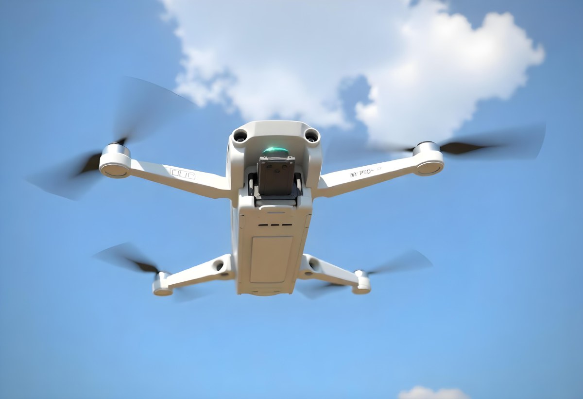 A Blue Dji Mini 3 Pro Drone With Blue Propellers In Mid Air Against A Bright Blue Sky With Scattered White Clouds 32 506d