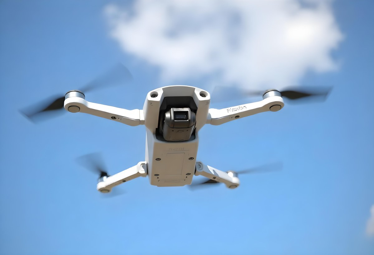 A Blue Dji Mini 3 Pro Drone With Blue Propellers In Mid Air Against A Bright Blue Sky With Scattered White Clouds 35 2bf3