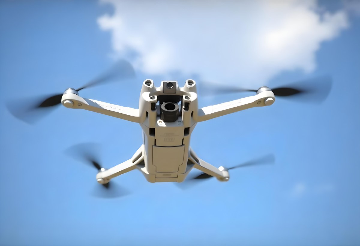 A Blue Dji Mini 3 Pro Drone With Blue Propellers In Mid Air Against A Bright Blue Sky With Scattered White Clouds 36 F807