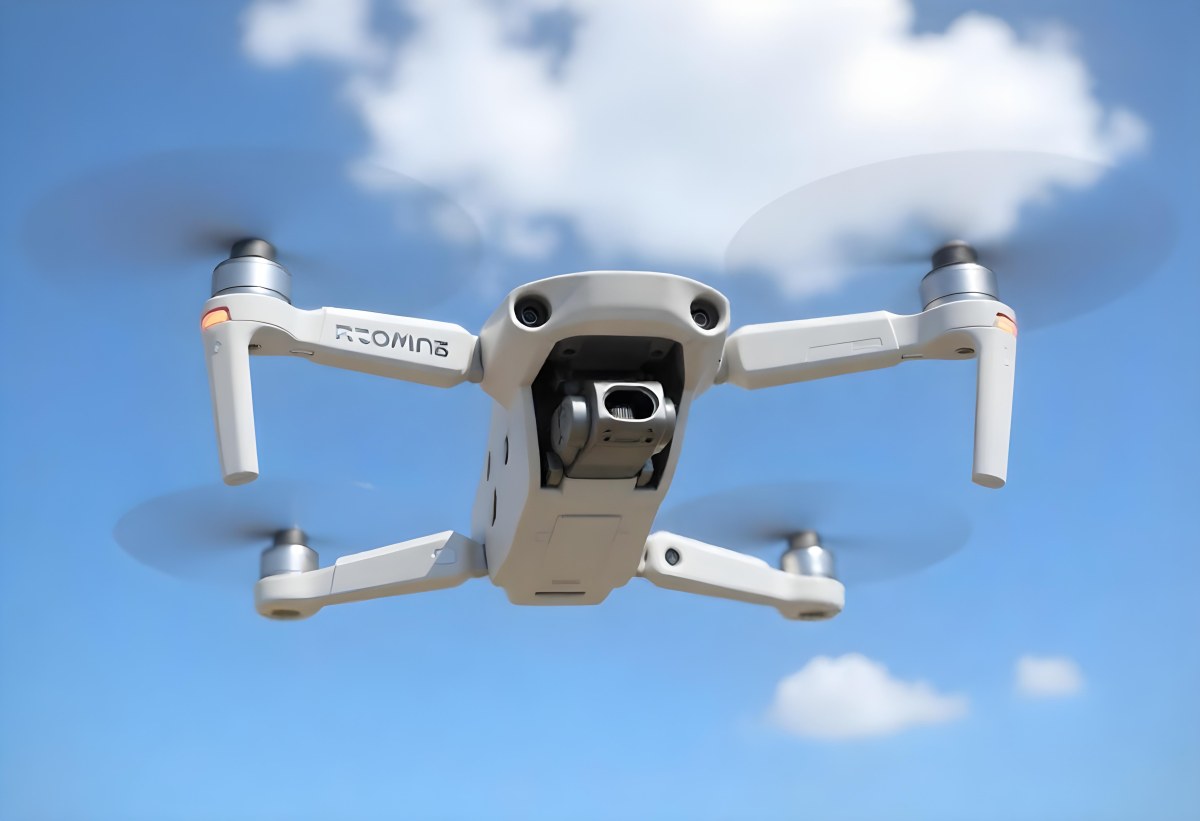 A Blue Dji Mini 3 Pro Drone With Blue Propellers In Mid Air Against A Bright Blue Sky With Scattered White Clouds 39 5404