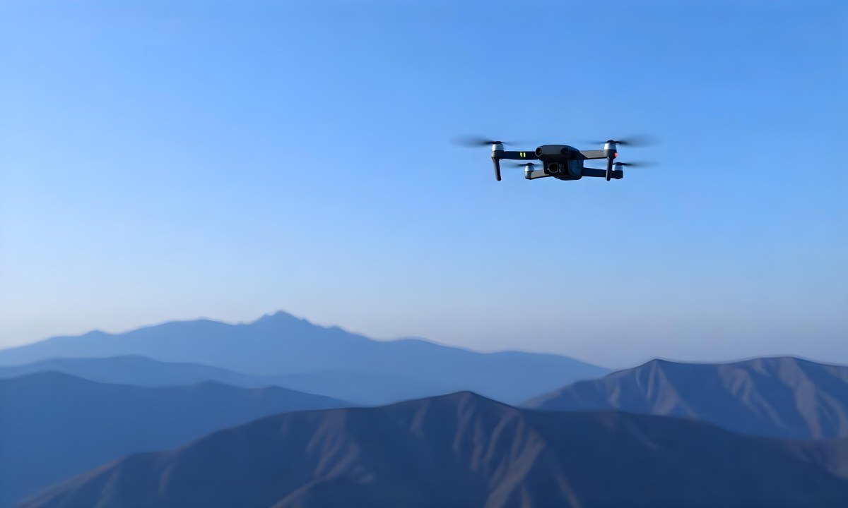 A Blue Drone Flying Over The Mountains With Mountains In The Background And A Clear Blue Sky 22 1785