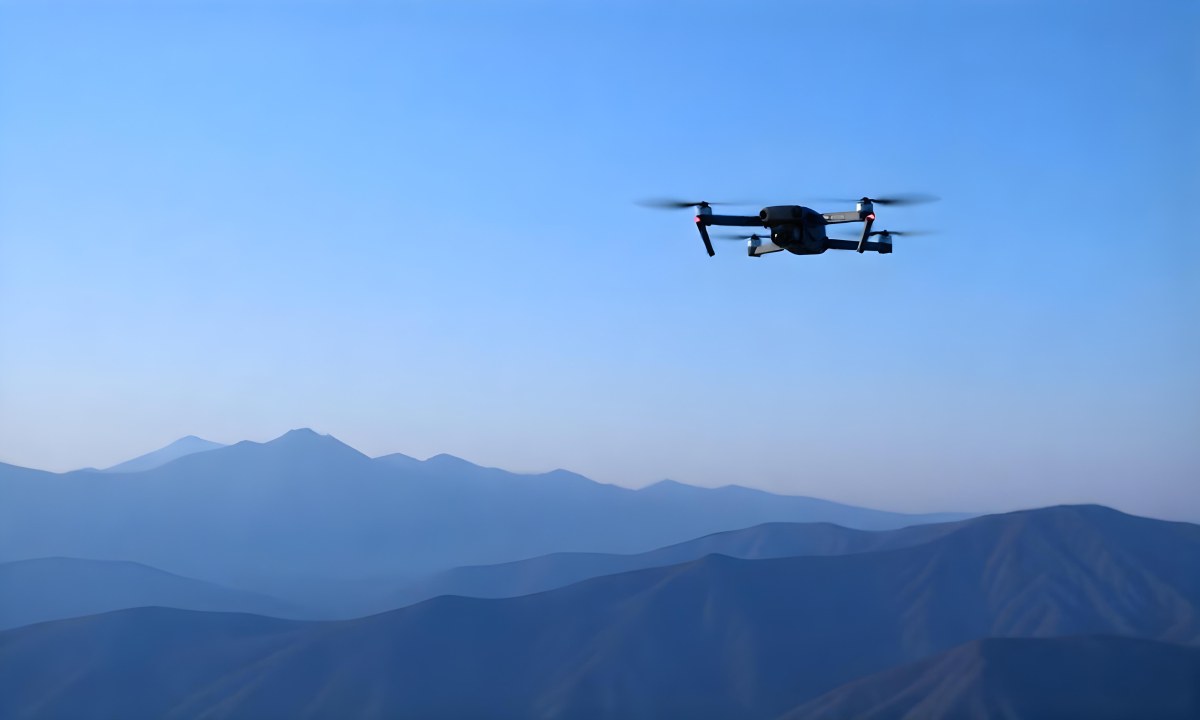 A Blue Drone Flying Over The Mountains With Mountains In The Background And A Clear Blue Sky 23 954b