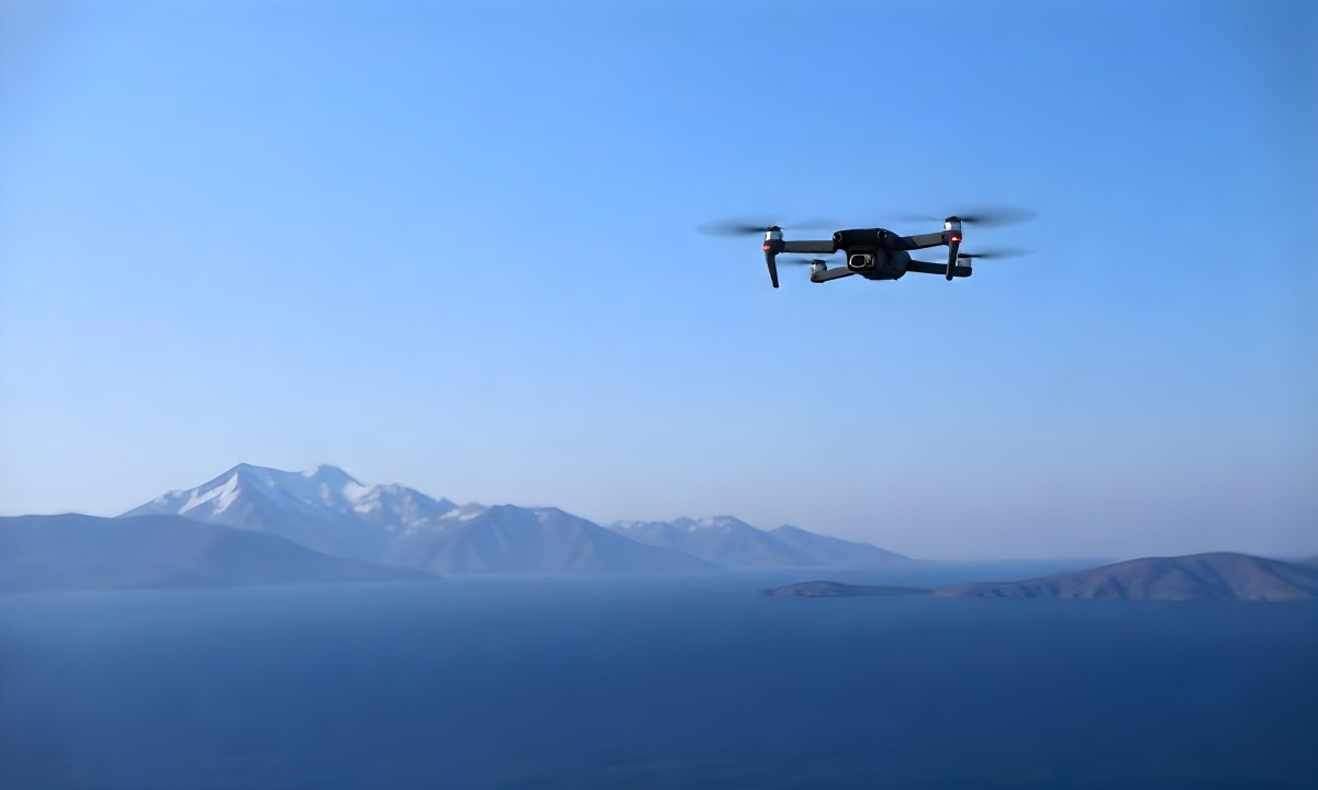 A Blue Drone Flying Over The Mountains With Mountains In The Background And A Clear Blue Sky 9 C160