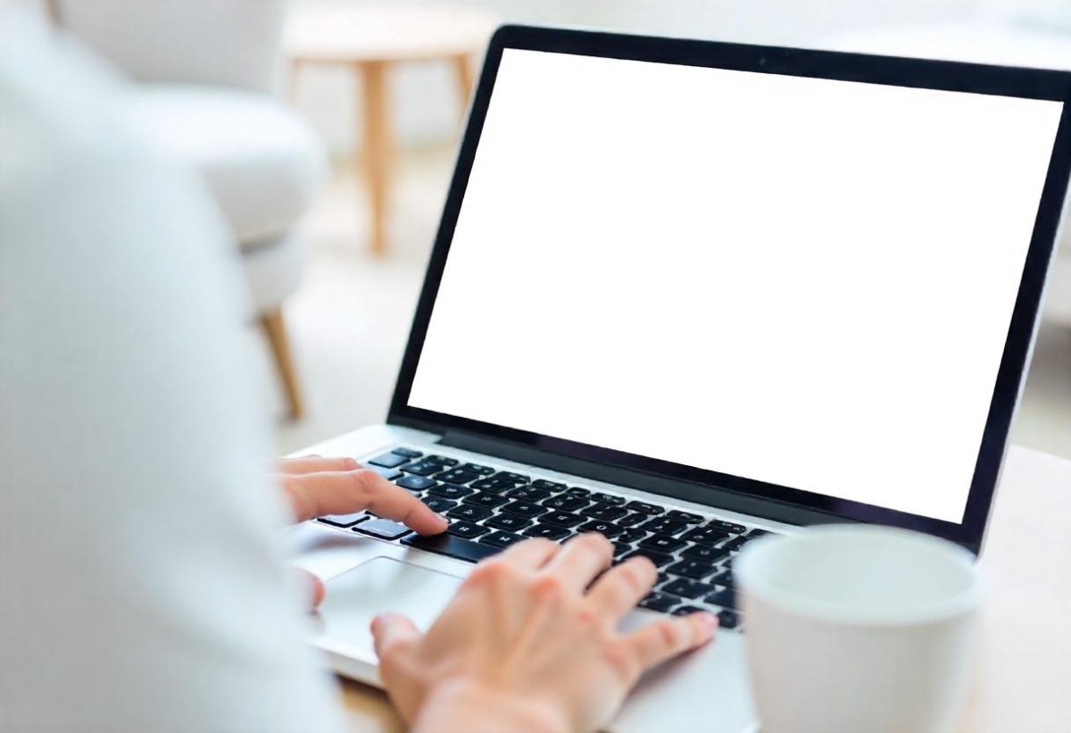 A Brown Skin Hand Holding A Blue Credit Card Over A Laptop The Background Is Blurred And Looks Like An Office 19 F79a