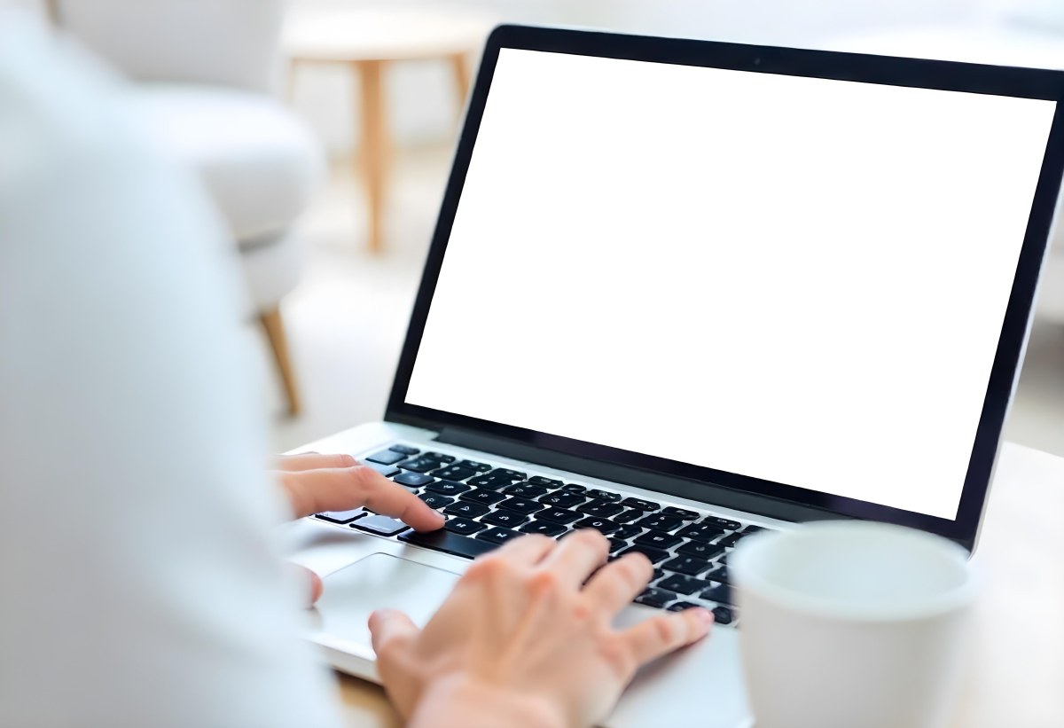 A Brown Skin Hand Holding A Blue Credit Card Over A Laptop The Background Is Blurred And Looks Like An Office 20 5423