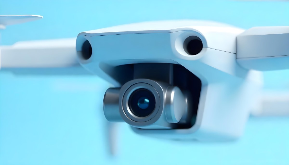 A Close Up Of A Drone Camera With A Lens And Blue Body Mounted On A White Drone With A Light Blue Background 11 1b08