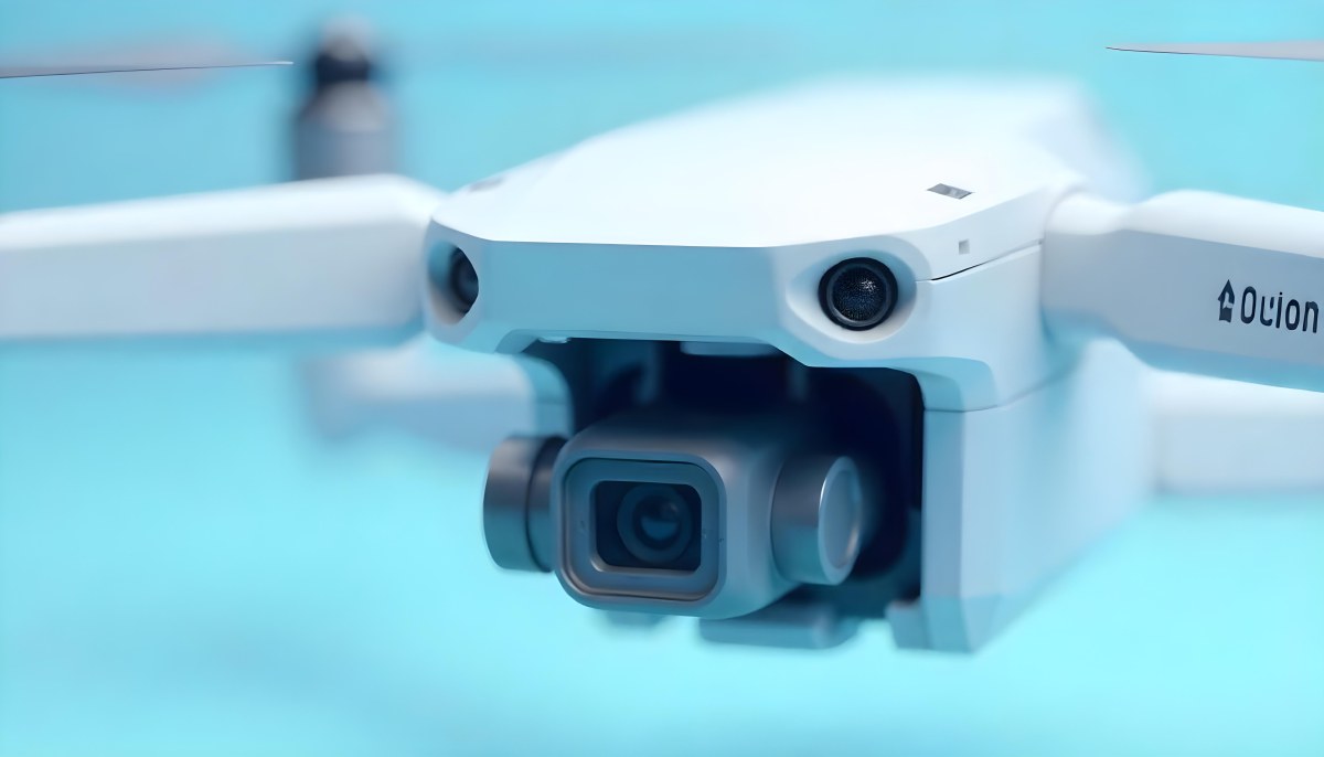 A Close Up Of A Drone Camera With A Lens And Blue Body Mounted On A White Drone With A Light Blue Background 21 6aa1