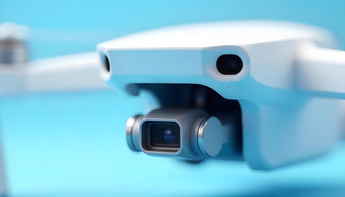 A Close Up Of A Drone Camera With A Lens And Blue Body Mounted On A White Drone With A Light Blue Background 24 C933