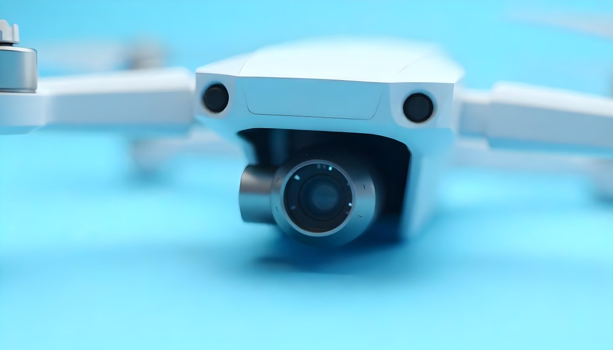A Close Up Of A Drone Camera With A Lens And Blue Body Mounted On A White Drone With A Light Blue Background 26 159f