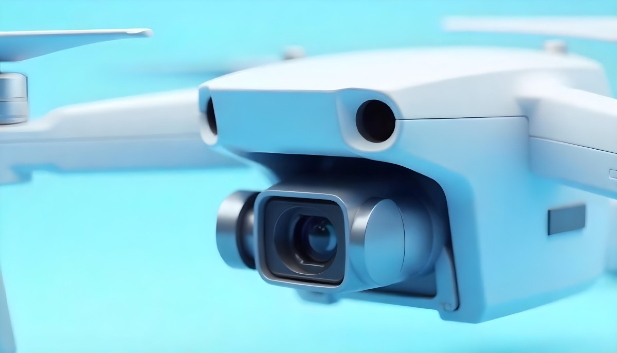 A Close Up Of A Drone Camera With A Lens And Blue Body Mounted On A White Drone With A Light Blue Background 27 F73f