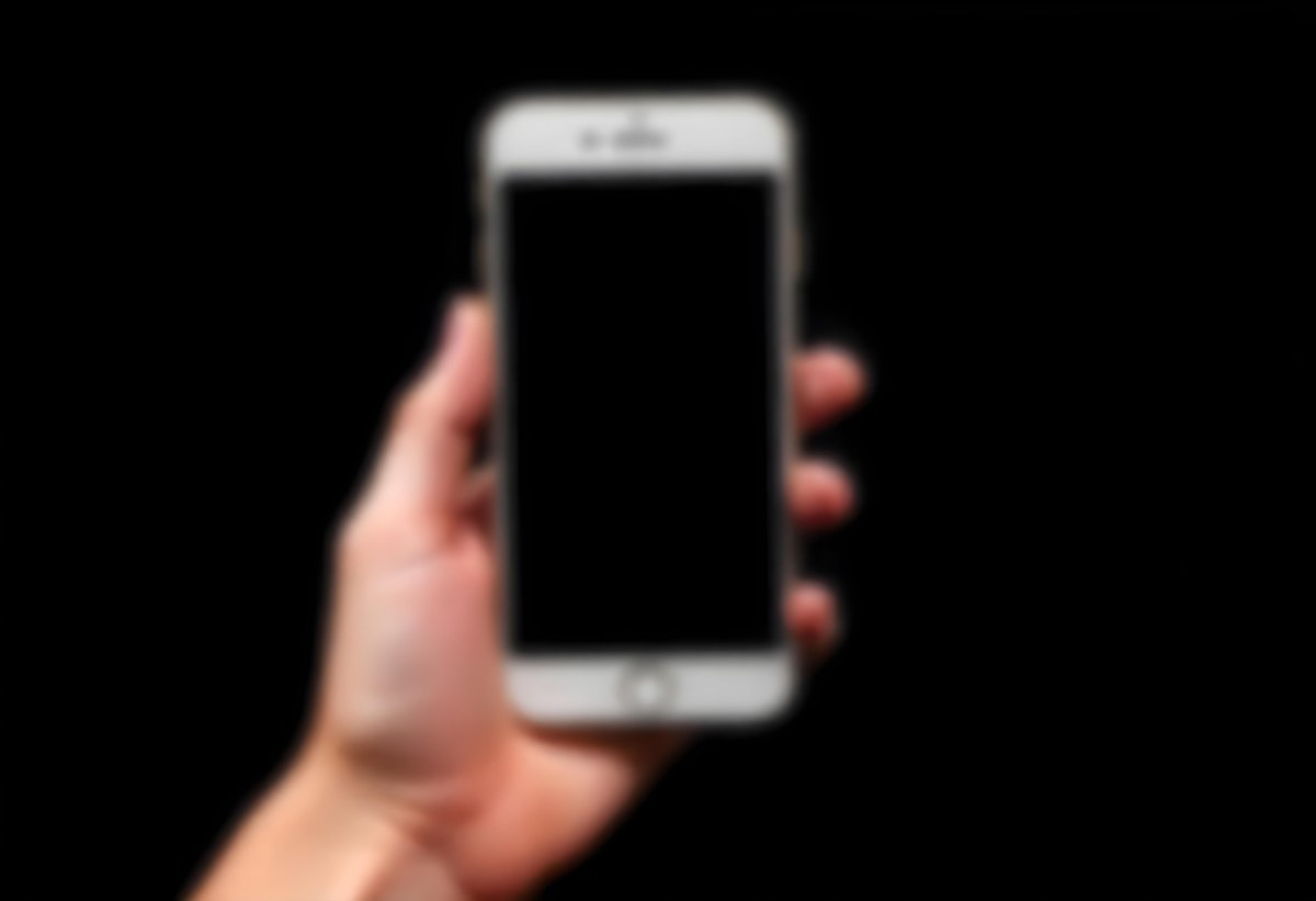 A Fair Skinned Hand Holding A White Smartphone With A Blank Black Screen Isolated On A Black Background 5 8073