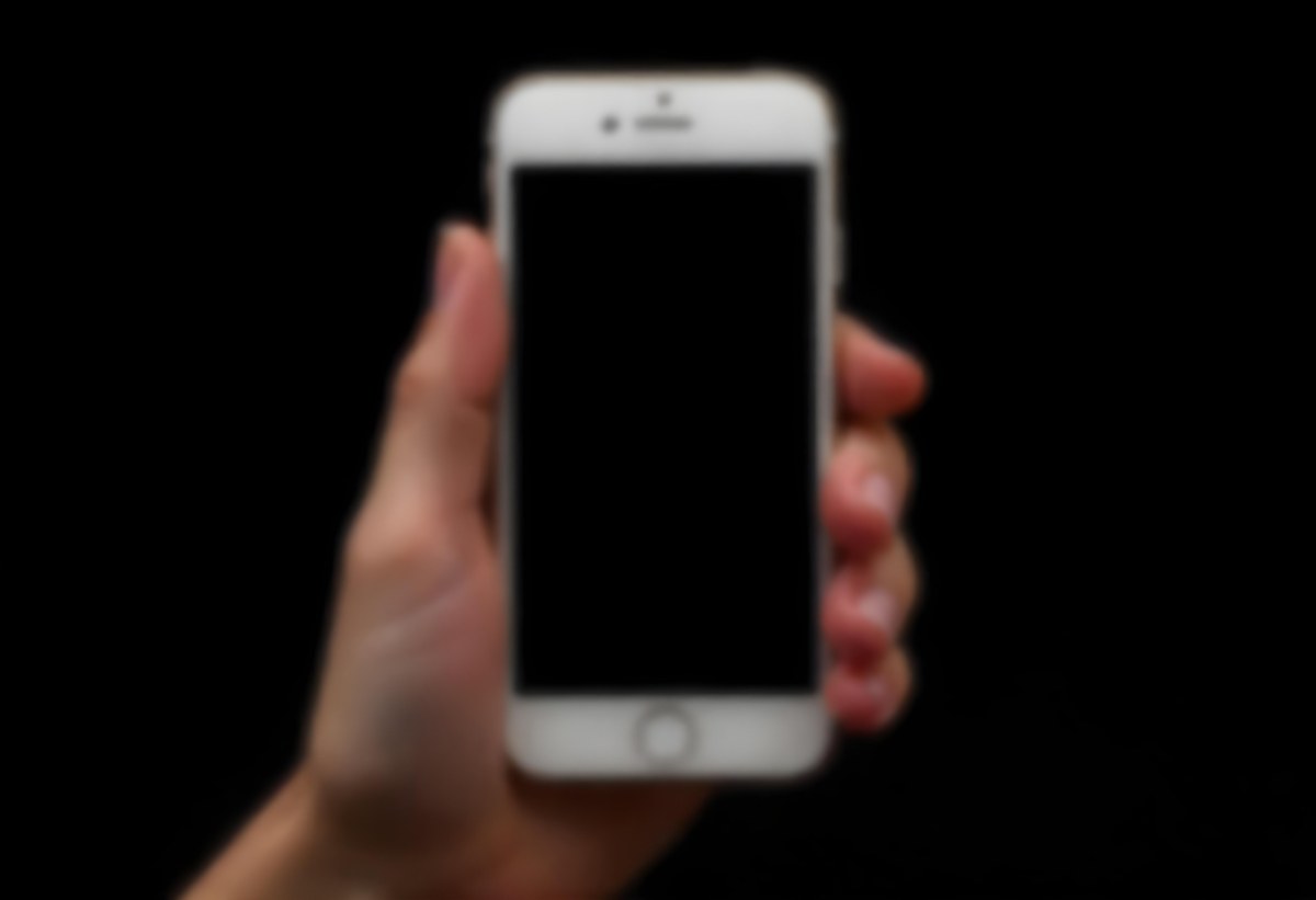 A Fair Skinned Hand Holding A White Smartphone With A Blank Black Screen Isolated On A Black Background 6 97b1