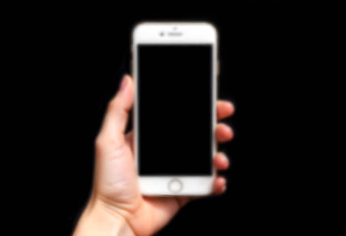A Fair Skinned Hand Holding A White Smartphone With A Blank Black Screen Isolated On A Black Background 8 Ce64
