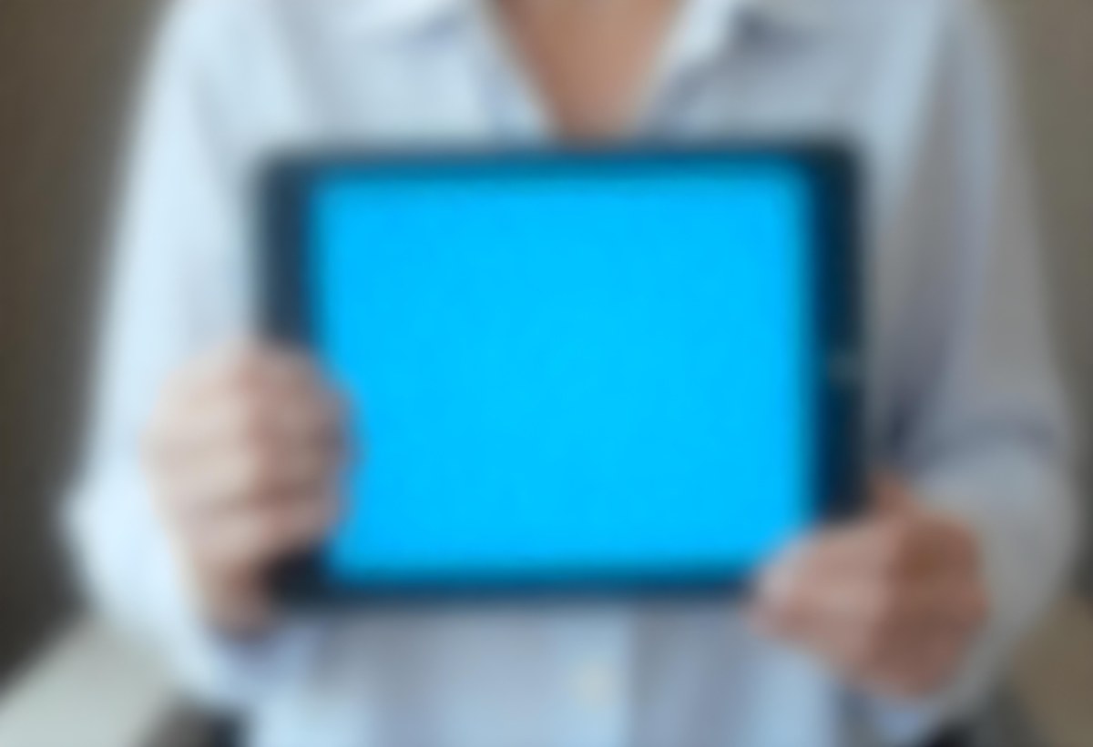 A Person Holding A Tablet With A Blank Blue Screen The Background Is Blurred And Out Of Focus The Person Is Wearing A White Shirt 5 E9f4