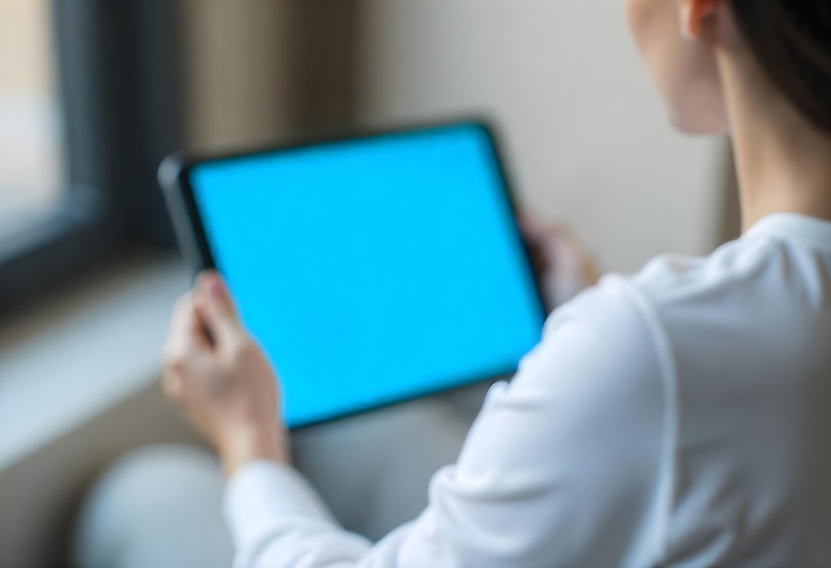 A Person Holding A Tablet With A Blank Blue Screen The Background Is Blurred And Out Of Focus The Person Is Wearing A White Shirt 9 5ded