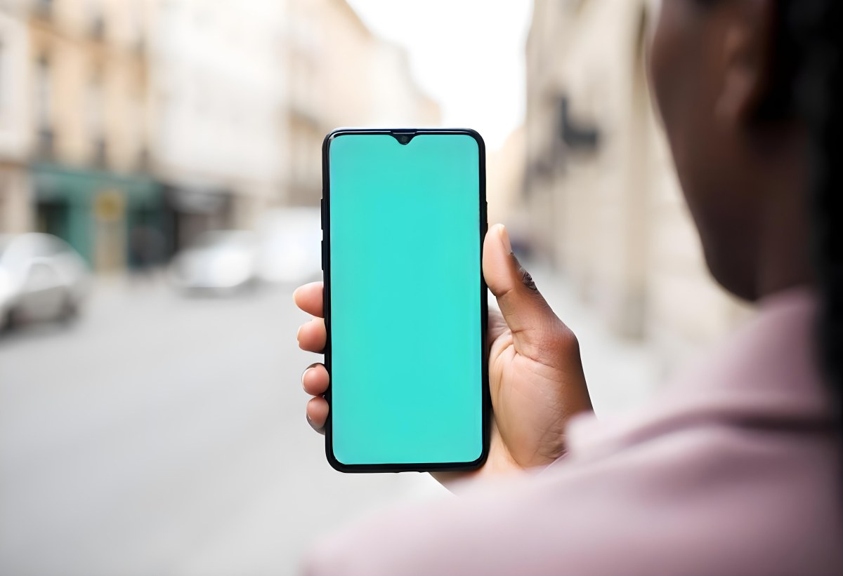 Black Man Holding A Smartphone With A Blank Turquoise Screen The Background Is A Blurred City Street 5 3581